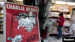 FILE - The front page of an issue of the satirical French weekly Charlie Hebdo entitled "C'est Reparti" ("Here we go again"), is displayed at a kiosk in Nice, Feb. 25, 2015. 