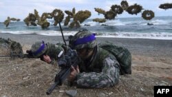 South Korean Marines take position on a beach as amphibious assault vehicles fire smoke shells during a joint landing operation by US and South Korean Marines in the southeastern port of Pohang on April 2, 2017.