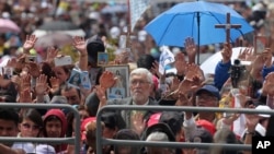 People raise their hands as Pope Francis blesses them after Mass at Bicentennial Park in Quito, Ecuador, July 7, 2015. 
