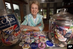 FILE - Judy Galluzzo poses with campaign buttons she’s collected over the years, in Salem, N.H.