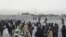 FILE - Stranded people wait at the Spin Boldak border crossing point guarded by security personnel in Pakistan's border town of Chaman, July 16, 2021. Taliban insurgents closed the crossing point August 6, 2021. 