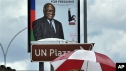 People walk under an election poster of the ruling South West African People's Organization (SWAPO), showing the incumbent President Hifikepunye Pohamba in Katatura, outside Windhoek, 25 Nov 2009