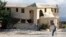 FILE - A man walks on crutches past a building destroyed by the earthquake in Leogane, Haiti, Dec. 12, 2010.