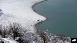 Dua warga Afghanistan berjalan di atas salju di distrik Paghman, Kabul (4/1). (AP/Rahmat Gul)