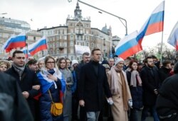 FILE - Russian opposition leader Alexei Navalny, center, his wife Yulia, right of him, and opposition activist Lyubov Sobol, second from left, take part in a march in Moscow, Russia, Feb. 29, 2020.
