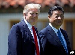 FILE - President Donald Trump and Chinese President Xi Jinping walk together after their meetings at Mar-a-Lago in Palm Beach, Fla., April 7, 2017.