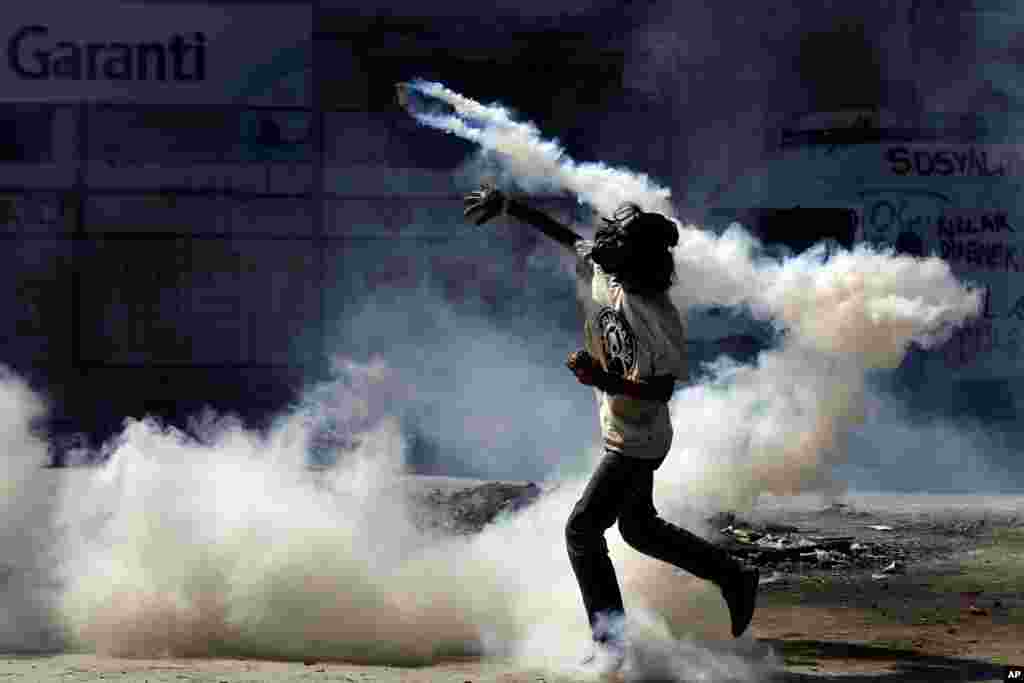A protester throws a tear gas canister back at police during clashes in Taksim Square in Istanbul, June 11, 2013. 