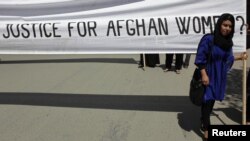 Seorang wanita berunjuk rasa di Kabul (11/7) dengan membawa spanduk yang menyuarakan protes atas eksekusi seorang perempuan oleh anggota Taliban di wilayah Parwan, Afghanistan.