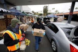 Volunteers load up vehicles at a food distribution center April 17, 2020, in the Crenshaw district of Los Angeles. As the coronavirus drives unemployment, food banks have seen a spike.