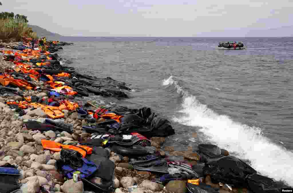 Syrian refugees arrive on a beach covered with life vests and deflated dinghies on the Greek island of Lesbos.