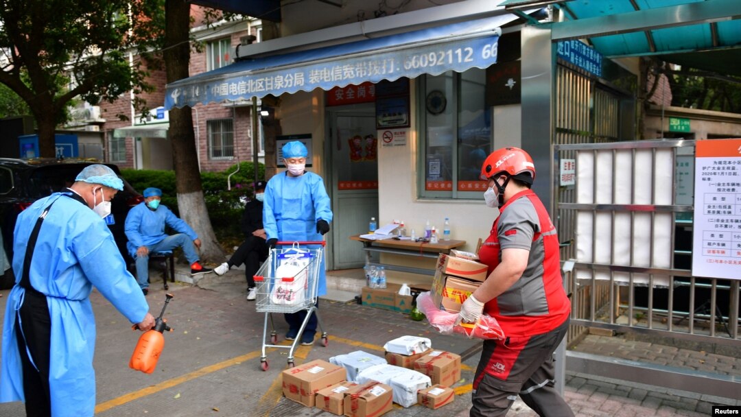 봉쇄된 중국 상하이 시내에서 지난 18일 물류업체 관계자들이 주거 지역 앞에 물품을 배송하고 있다.