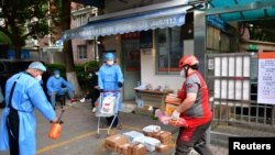 봉쇄된 중국 상하이 시내에서 지난 18일 물류업체 관계자들이 주거 지역 앞에 물품을 배송하고 있다.