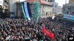 Anti-Syrian regime protesters gather at a square as they hold an Arabic banner, center, reading, 'hey, the miserable, the tyrant, what else,' during a demonstration at the mountain resort town of Zabadani, Syria, near the Lebanese border, January 20, 2012