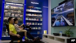 Un vendedor ayuda a un niño a probar un videojuego en una tienda en Beijing, el lunes 27 de julio de 2015. 