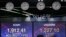 A currency trader wearing a face mask walks by screens at the foreign exchange dealing room in Seoul, South Korea, May 12, 2020. 