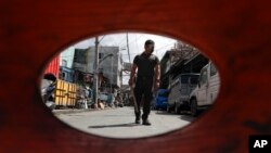 A policeman patrols inside a village that was placed under lockdown as the government implements stricter measures to prevent the spread of the coronavirus in Manila, Philippines on Monday, March 22, 2021.