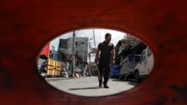 A policeman patrols inside a village that was placed under lockdown as the government implements stricter measures to prevent the spread of the coronavirus in Manila, Philippines on Monday, March 22, 2021.