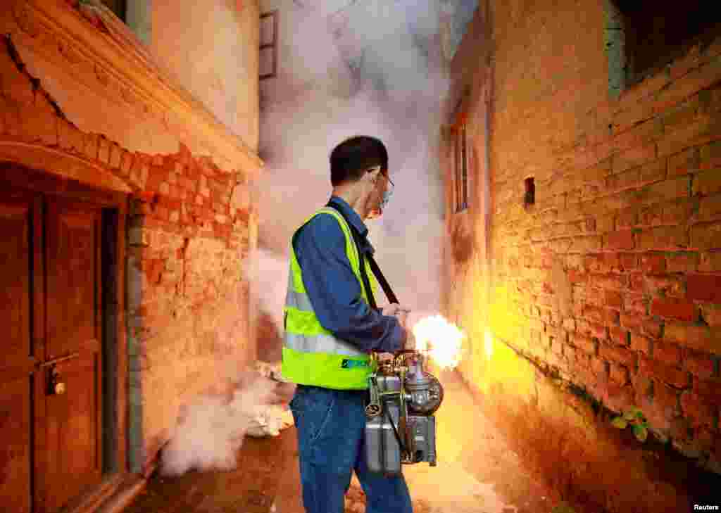 A worker fumigates a residential area to prevent the spread of the dengue fever and other mosquito-borne diseases in Kathmandu, Nepal.