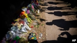 FILE - Visitors cast shadows at a memorial to the victims of the Astroworld concert in Houston on Nov. 7, 2021. 