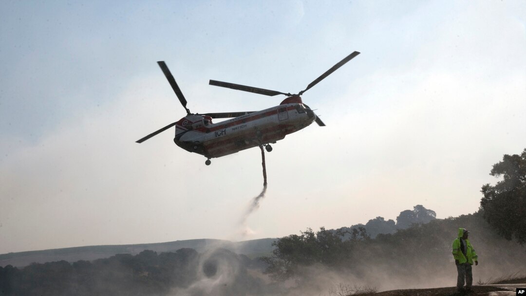 A helicopter draws water from a pond to help put out a fire near Napa, California, Oct. 12, 2017.