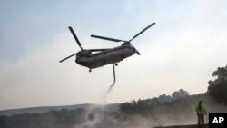A helicopter draws water from a pond to help put out a fire near Napa, California, Oct. 12, 2017.