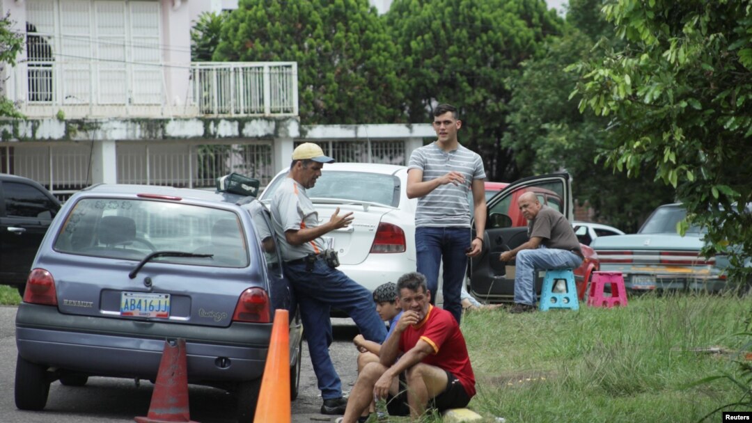 ARCHIVO - Personas esperan llenar de combustible sus vehículos en las afueras de una estación de gasolina de la compañía PDVSA en San Cristobal, Venezuela.