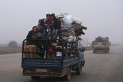FILE - Civilians ride in a truck as they flee Maaret al-Numan, Syria, ahead of a government offensive, Dec. 23, 2019. The M5 strategic highway is vital for Syria’s economy as well as for moving troops.