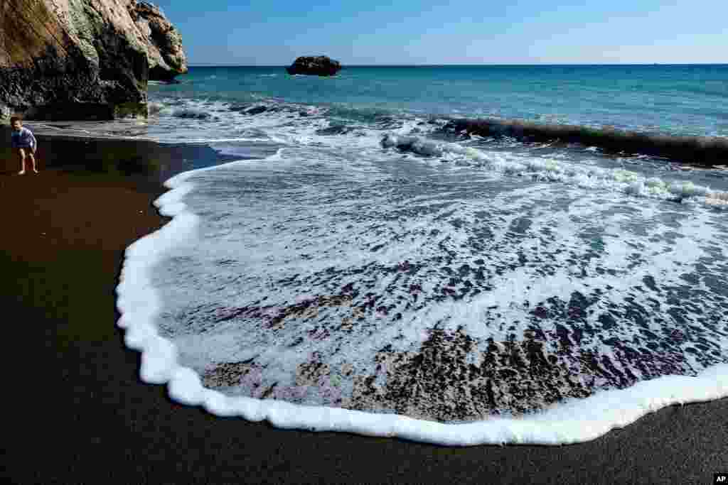 A boy plays in the surf adjacent to Aphrodite&#39;s Rock, the spot where&nbsp;the ancient goddess Aphrodite was born according to ancient Greek mythology, near Cyprus&#39; coastal resort town of Paphos, March 22, 2015.