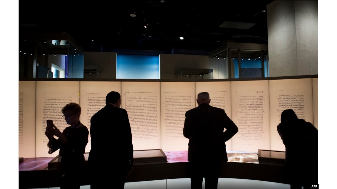 FILE - FILE - Visitors look at an exhibit about the Dead Sea Scrolls during a media preview of the Museum of the Bible in Washington, D.C., Nov. 14, 2017.