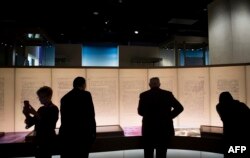 FILE - FILE - Visitors look at an exhibit about the Dead Sea Scrolls during a media preview of the Museum of the Bible in Washington, D.C., Nov. 14, 2017.