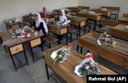 FILE-in this May 16, 2021 file photo, Schoolgirls sit inside a classroom with bouquets of flowers on empty desks as a tribute to those killed in the brutal May 8 bombing of the Syed Al-Shahda girls school, in Kabul, Afghanistan.