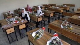 FILE-in this May 16, 2021 file photo, Schoolgirls sit inside a classroom with bouquets of flowers on empty desks as a tribute to those killed in the brutal May 8 bombing of the Syed Al-Shahda girls school, in Kabul, Afghanistan.