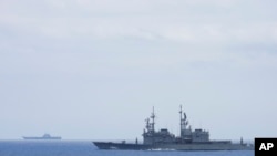 In this photo released by the Taiwan Ministry of National Defense, Taiwanese navy ship Keelung, foreground, a U.S.-made Kidd Class destroyer, monitors the Chinese aircraft carrier Shandong, background, near the Taiwanese waters in September 2023. 