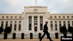 FILE - A man walks past the Federal Reserve Bank in Washington, D.C.
