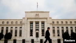 FILE - A man walks past the Federal Reserve Bank in Washington, D.C.