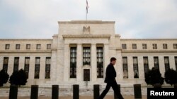 FILE - A man walks past the Federal Reserve Bank in Washington, D.C.