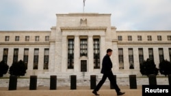 FILE - A man walks past the Federal Reserve Bank in Washington, D.C.