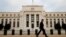FILE - A man walks past the Federal Reserve Bank in Washington, D.C.