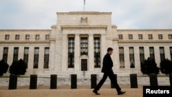 FILE - A man walks past the Federal Reserve Bank in Washington, D.C.