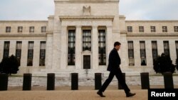 FILE - A man walks past the Federal Reserve building in Washington, D.C., Dec. 16, 2015.