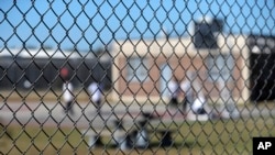 FILE - Detainees sit in a yard inside the Winn Correctional Center in Winnfield, La., Sept. 26, 2019.