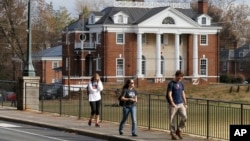 FILE - In this Monday, Nov. 24, 2014, file photo, University of Virginia students walk to campus past the Phi Kappa Psi fraternity house at the University of Virginia in Charlottesville, Va. Rolling Stone retracted a story of sexual attack at the fraternity. (AP Photo/Steve Helber, File)