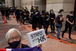 A woman holds a placard as supporters queue up outside a court to try to get in for a hearing in Hong Kong, March 1, 2021. Hong Kong police on Monday brought 47 pro-democracy activists to court on charges of conspiracy to commit subversion.