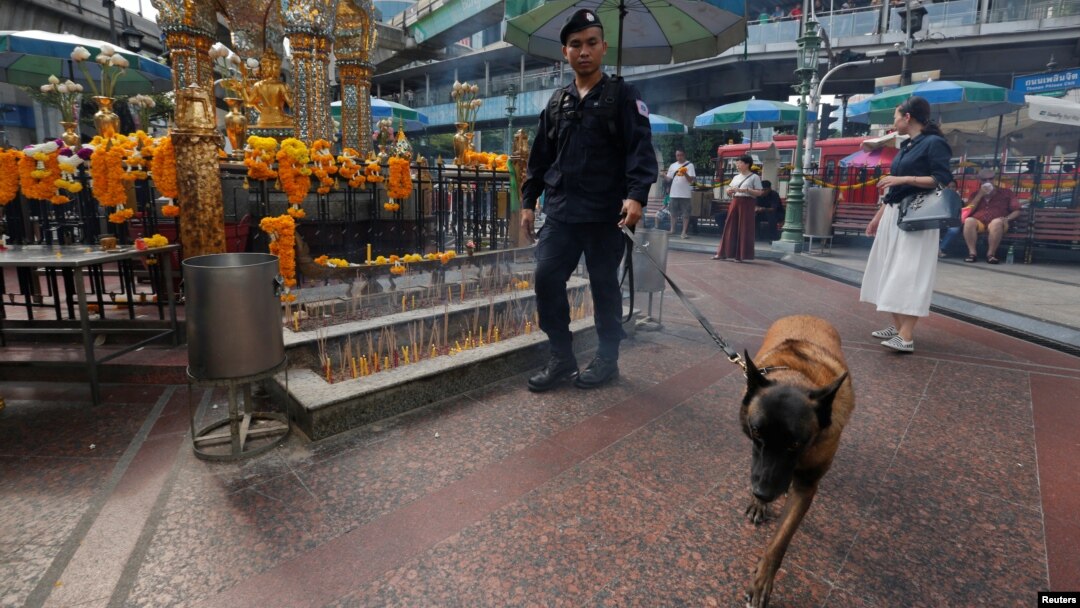 A Thai police officer and his dog inspect around the Erawan shrine during the first anniversary of the shrine's bombing in central Bangkok, Thailand, Aug. 17, 2016. Security has been stepped up at tourist sites.