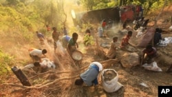 FILE - Women and children separate grain from soil after a spill from a truck in Machinga, Malawi, May 24, 2016. The desire to escape poverty, experts say, is one of the factors that lead young women into the grasp of human traffickers.