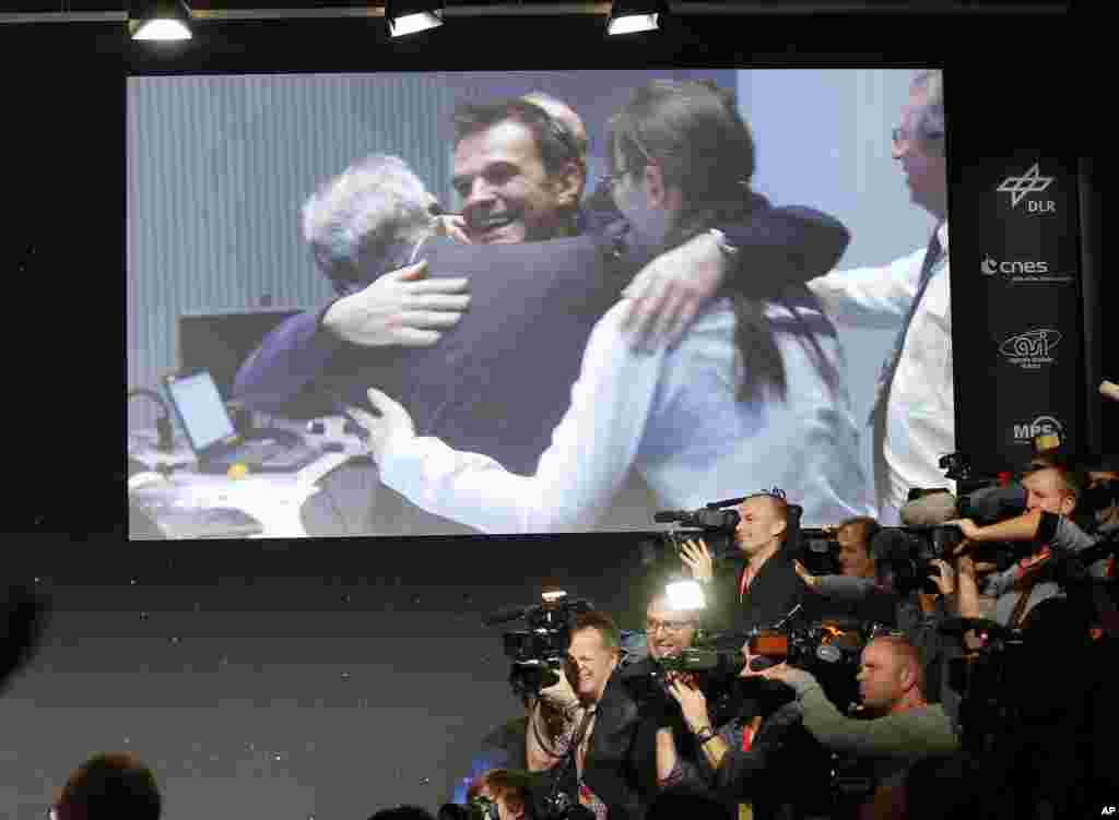 Celebrating scientists in the main control room appear on a video screen at the European Space Agency after the first unmanned spacecraft Philae landed on a comet called 67P/Churyumov-Gerasimenko, in Darmstadt, Germany, Nov. 12, 2014.