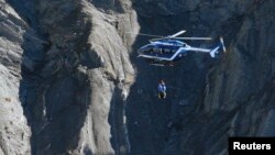 A French Gendarmerie rescue helicopter winches rescue workers over the debris of the Airbus A320 at the site of the crash, near Seyne-les-Alpes, French Alps, March 27, 2015. 