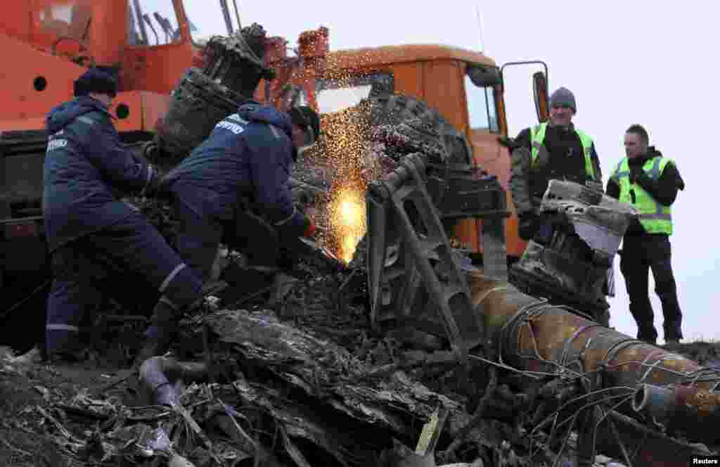 Local workers cut wreckage of the Malaysia Airlines Flight MH17 at the site of the plane crash near the settlement of Grabovo in the Donetsk region, Nov. 16, 2014.