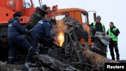 Local workers cut wreckage of the Malaysia Airlines Flight MH17 at the site of the plane crash near the settlement of Grabovo in the Donetsk region, Nov. 16, 2014.