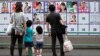 Une famille regarde les affiches des candidats devant un bureau de vote à Tokyo, au Japon, le 5 juillet 2020